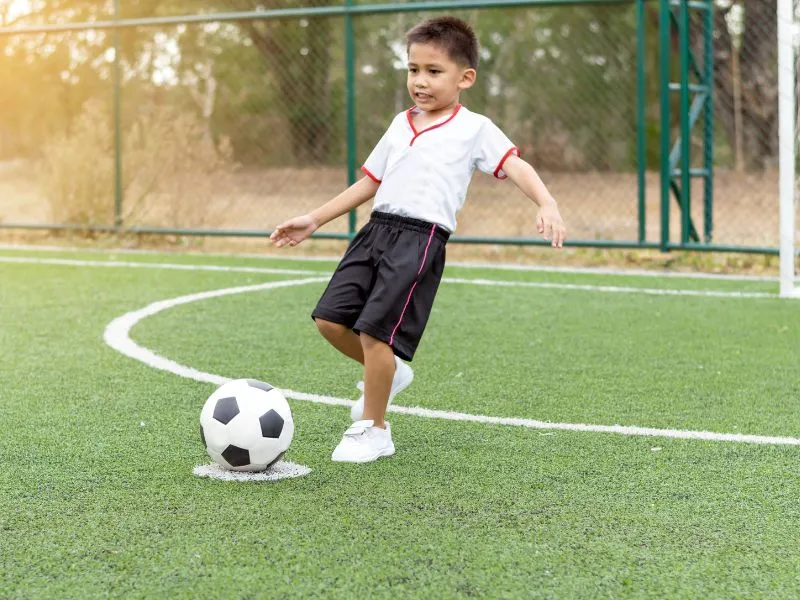 anak kecil sedang bermain bola, meskipun kesakitan.