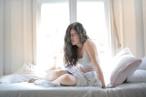 gambar seorang wanita seadng memegang perutnya karena kesakitan GERD. Gambar ini bertujuan untuk artikel website Klinik Dr. Indrajana yang berjudul Pentingnya Pencegahan GERD dengan Gaya Hidup Sehat.