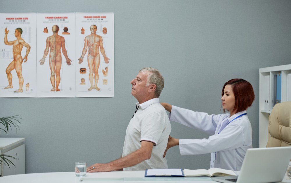 Gambar seoraang dokter ortopedi sedang cek tulang belakang pasien. Gambar dipakai untuk keperluan artikel Klinik Utama DR Indrajana.