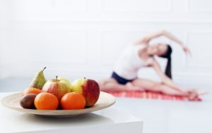 gambar buah dengan background wanita sedang melakukan yoga.